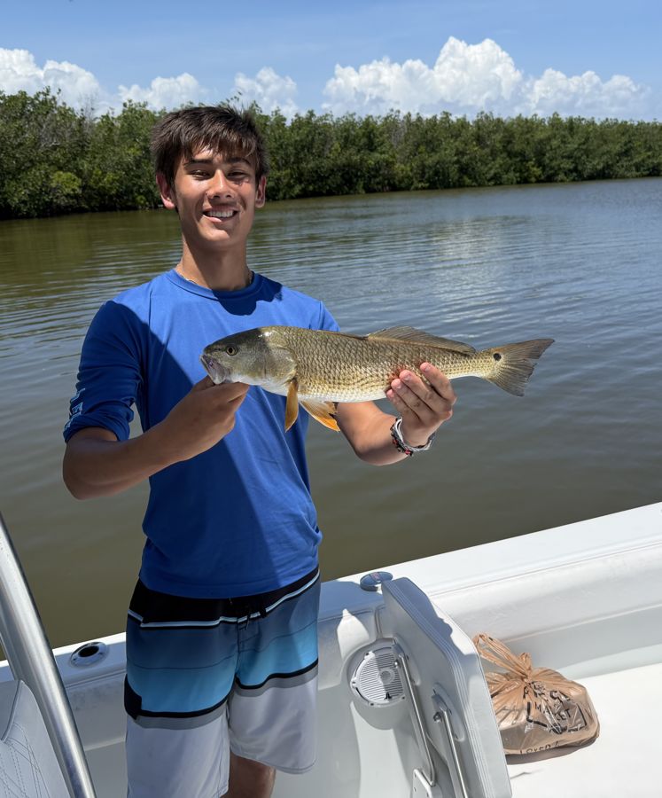 A young angler holding a redfish on the Indian River Lagoon